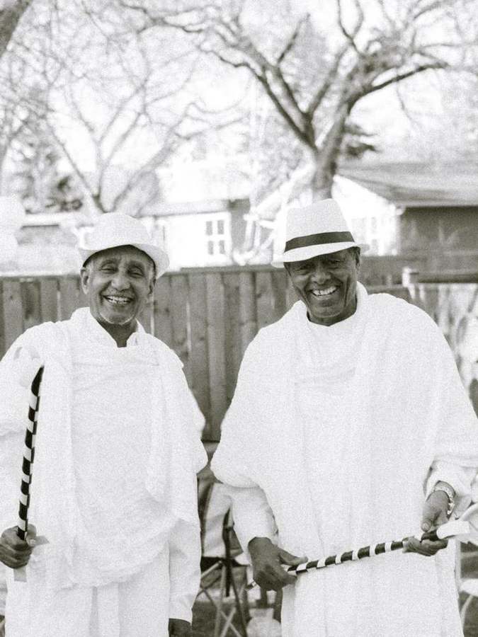 Two elders smiling, holding traditional canes