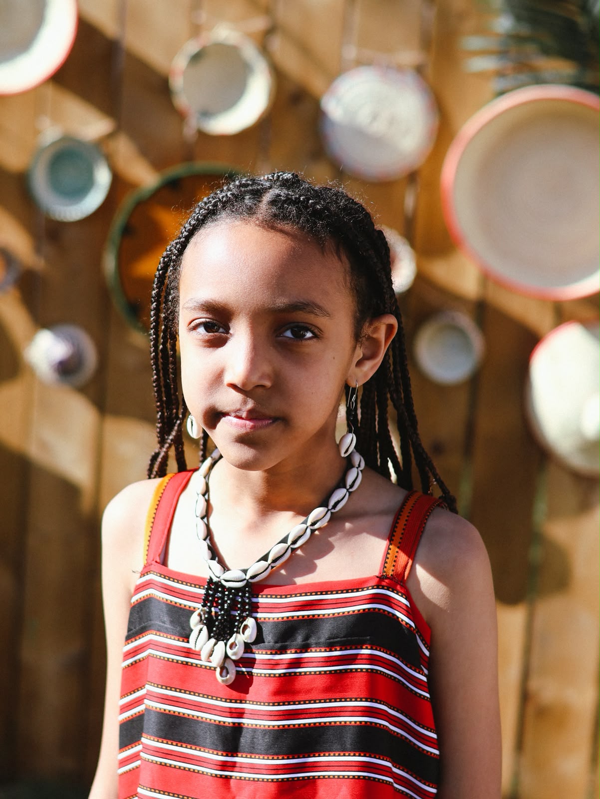 Young girl in a striped dress wearing a cowrie shell necklace