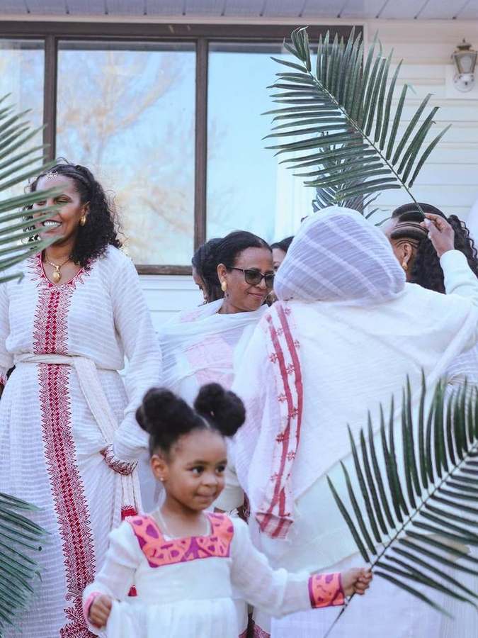 A woman with two young girls, palm branches in view