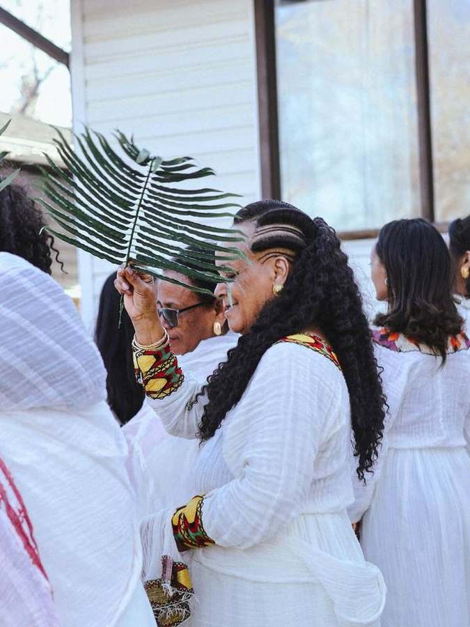 Woman holding up a palm branch, smiling among friends