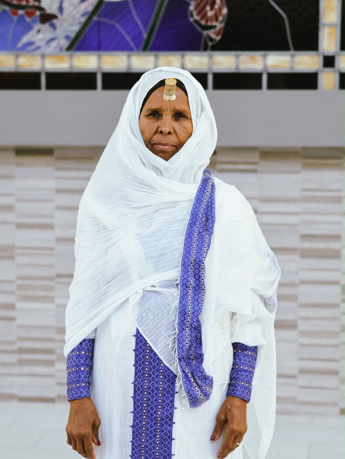 Elder woman in a white shawl with purple woven trim