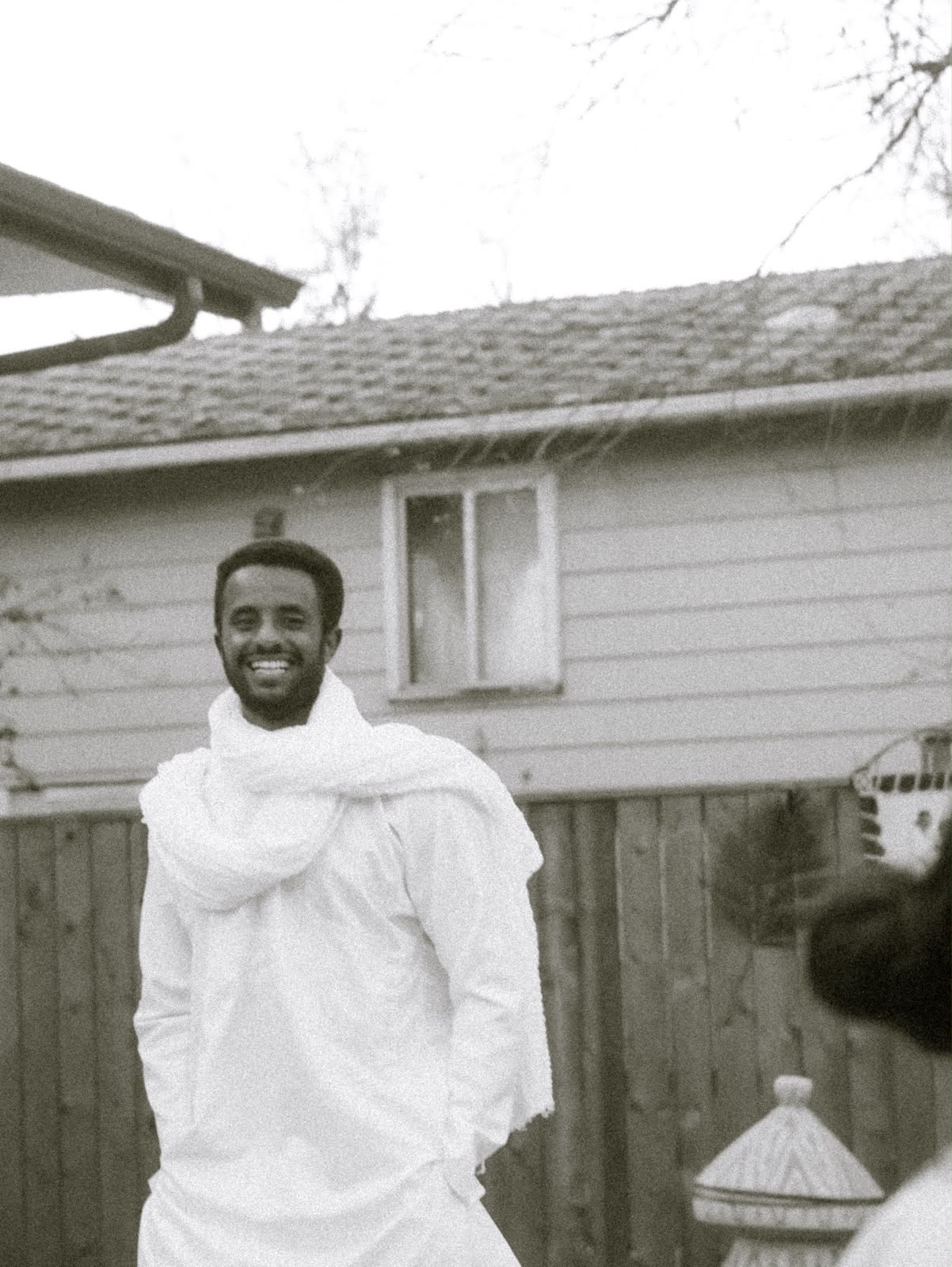 Man wrapped in a white shawl, smiling