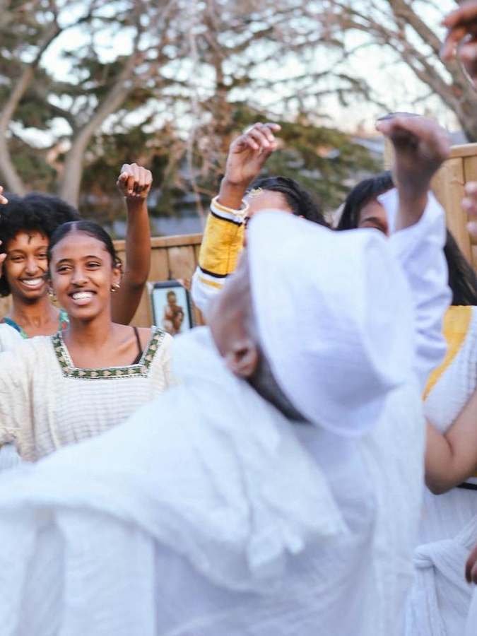Guests dancing with raised arms among the trees