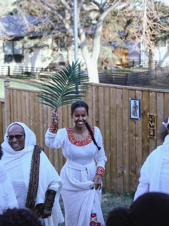 Woman holding a palm branch, smiling brightly