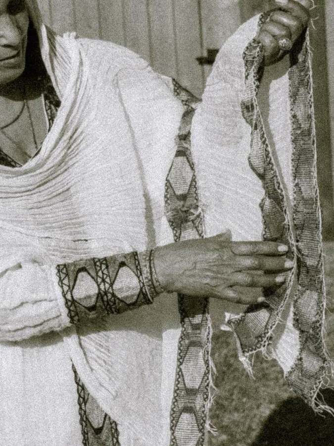 Detail of hands holding an embroidered scarf
